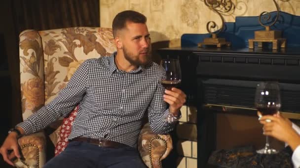 彼のガール フレンドに話している彼の手のワインのガラスが付いている日付にひげを生やした青年 — ストック動画