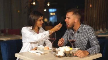Güzel çift aşık kafede oturup, kahve içme ve peynirli kek yeme. Genç kadın erkeğini besleniyor