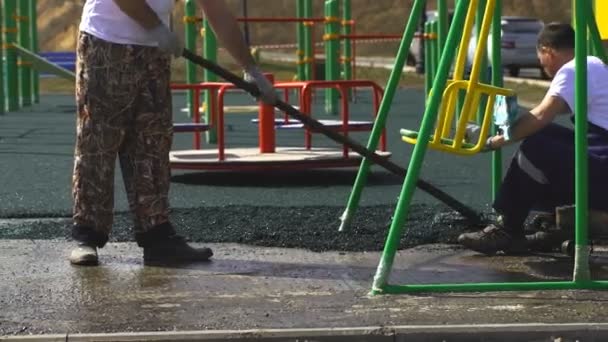 Pracownik szczotki pokrywa betonu, asfaltu gumowe podkład. — Wideo stockowe