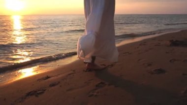 Beyaz sundress çıplak ayak yaz sahilde yürüyüş kadında. deniz dalgası yürüyen genç kadın bacak kadar kapatın