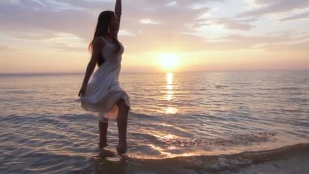 Une jeune femme sur la plage éclaboussant d'eau et se livre — Video