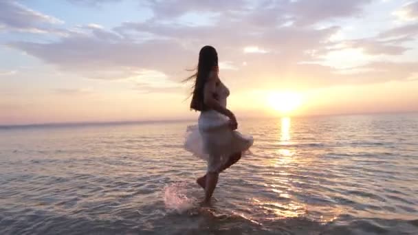 Young woman in sundress spinning in the water on the shore — Stock Video