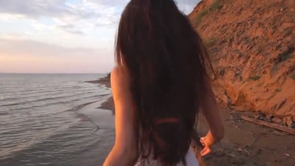 Hermosa morena con pelo largo corriendo en la playa al atardecer fondo — Vídeos de Stock