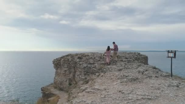 Вид с воздуха на романтическую прогулку пары возле скал — стоковое видео