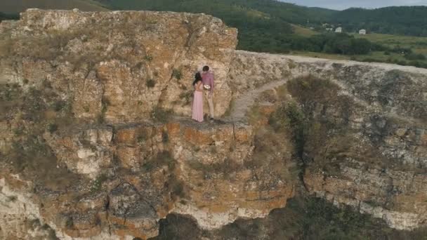 Vue aérienne sur une mariée magnifique, un marié embrassant et embrassant près des falaises avec une vue imprenable — Video