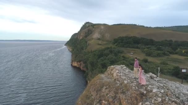 Luchtfoto op jonge paar staande op de kliffen rond de zee en de rotsen — Stockvideo