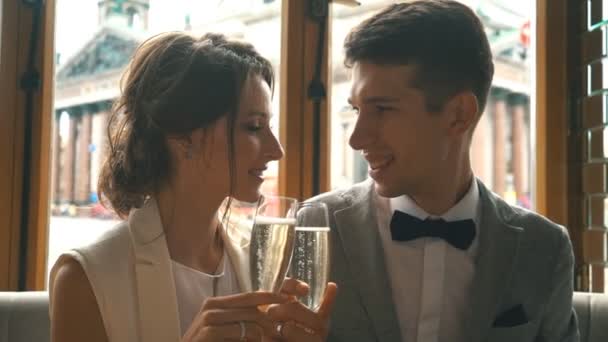 Молодожены целуются и пьют шампанское в ресторане — стоковое видео