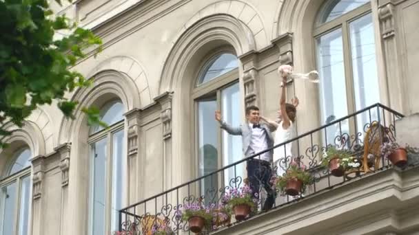 Bruid en bruidegom kussen staande op de oude stenen balkon — Stockvideo