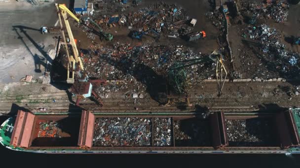 Vista aérea en una grúa de trabajo en un montón de chatarra cargará hierro — Vídeos de Stock