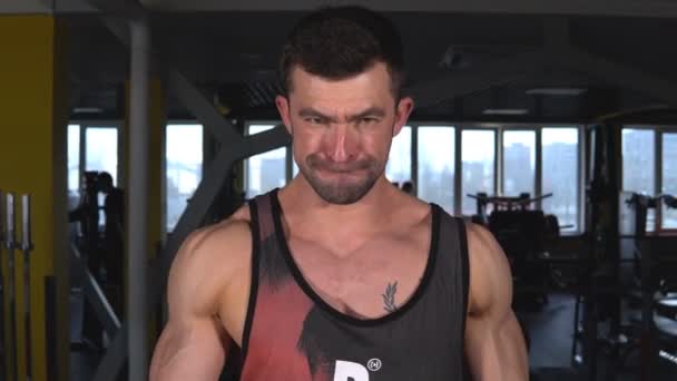 Hombre guapo con grandes músculos entrena en el gimnasio, ejercicios — Vídeo de stock