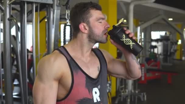 Молодой мускулистый человек пьет бутылку воды — стоковое видео