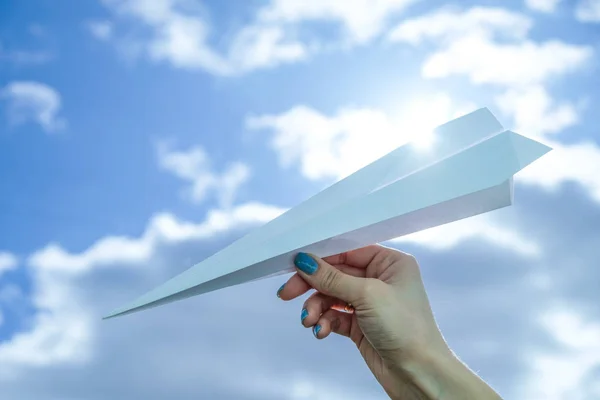 Taking flight! Hand holding paper airplane in the sky.