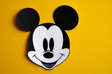 RUSSIA, ST.PETERSBURG - NOVEMBER 19, 2018: Black and white face of Mickey Mouse out of paper on a yellow background. clipart