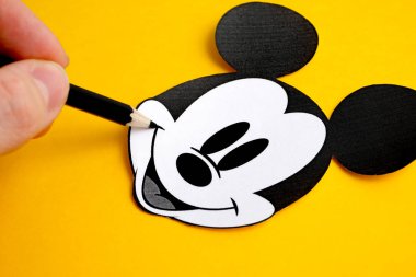 Rusya, St.Petersburg - 19 Kasım 2018: Mickey Mouse siyah ve beyaz yüz kağıt parmak yakınındaki tutun kalem sarı bir arka plan üzerinde 