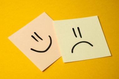 Ofiste iş arkadaşları arasındaki ilişki kavramı. Sevinç ve üzüntü sarı bir arka plan üzerinde yüzleri ile sarımsı sopa.