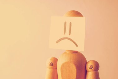 Mutsuz bir insan yüzü kavramı. Yüzünde hüzün görüntüsü ile bir etiket ahşap manken. Tonda.