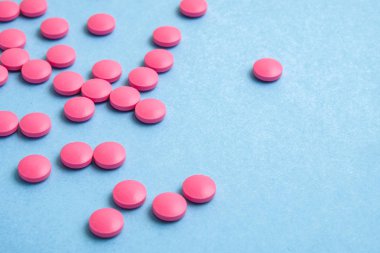 Mavi arka plan üzerinde dağınık pembe haplar. Yakın çekim.