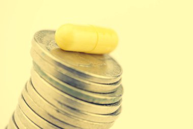 Beyaz bir arka plan üzerinde paralar bolca sarı kapsülünde. Yakın çekim. Tonda. Uyuşturucu iş kavramı.