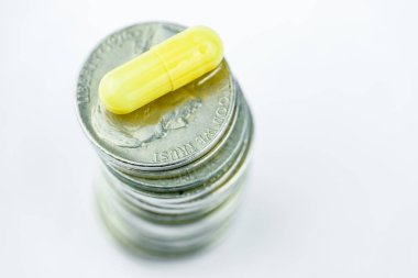 Beyaz bir arka plan üzerinde paralar bolca sarı kapsülünde. Yakın çekim. Uyuşturucu iş kavramı.