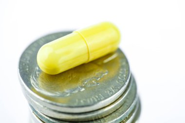 Beyaz bir arka plan üzerinde paralar bolca sarı kapsülünde. Yakın çekim. Uyuşturucu iş kavramı.