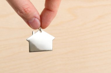 Satın alma veya kiralama veya ev ve Emlak sigortalanması kavramı. Evin arka plan beyaz saray doku üzerinde metal bir rakam parmak tutun.