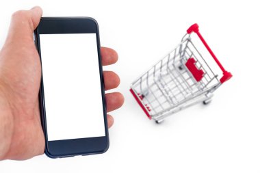Online bir akıllı telefon alışveriş kavramı. Erkek el bir telefon tutuyor. Beyaz bir arka plan üzerinde metal el arabası. yakın çekim.