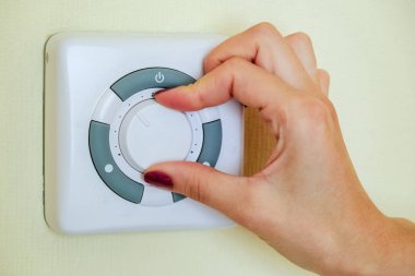 Kız el ile Klima otelde duvardaki konsoluyla sıcaklığını ayarlar.