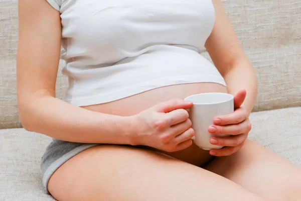Hamile Bir Kız Bir Shirt Kanepede Oturan Bir Beyaz Kupa — Stok fotoğraf