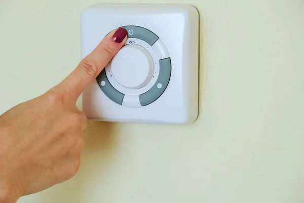 The girl push button power by finger of the air conditioner through the console on the wall in the hotel.