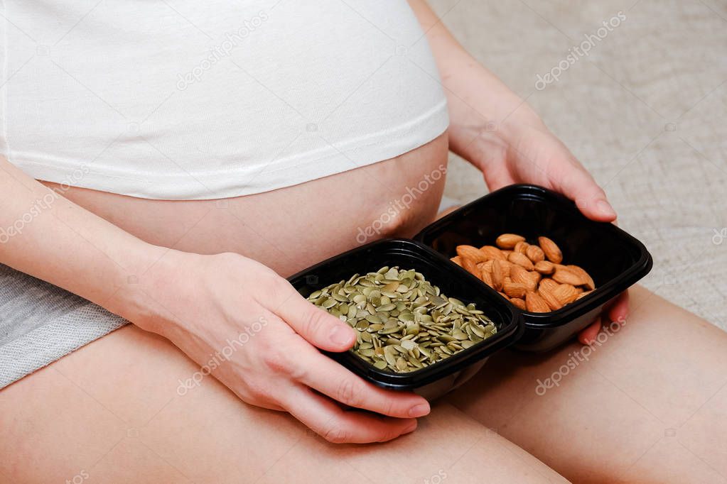 Pregnant woman with two bowls of nuts on the foot
