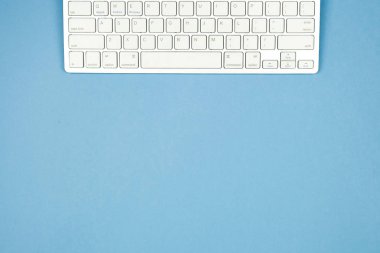 Kompakt beyaz kablosuz klavye mavi bir arka plan üzerinde. Kopya alanı.