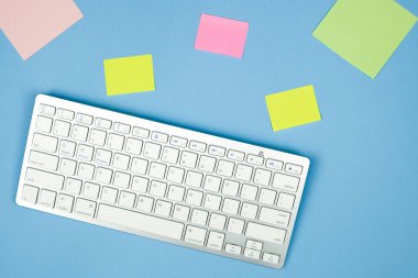 Kompakt beyaz kablosuz klavye çıkartmaları ile mavi bir arka plan üzerinde. Çoklu görev kavramı.