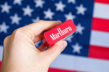 Rusya, St.Petersburg - 31 Ocak 2019: Yardım ABD bayrağı arka planı kırmızı bir paket Marlboro sigara tutuyor.