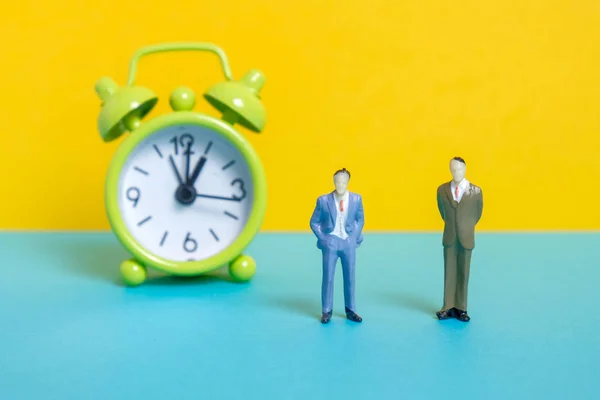 Men dummy next to a green vintage clock on a yellow background.