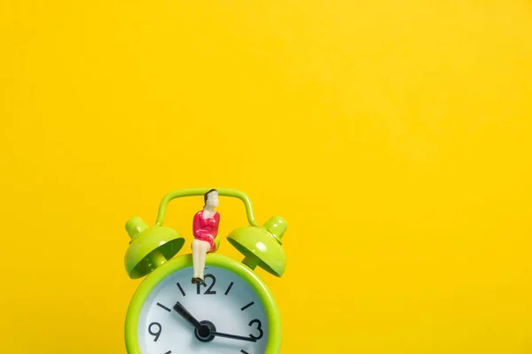 Maniquí de mujer de negocios sentado en verde reloj vintage sobre fondo amarillo . — Foto de Stock