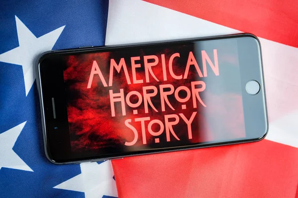 RUSSIA, ST.PETERSBURG - 11 de abril de 2019: Screensaver series American horror story on a smartphone on the background of the American flag . — Fotografia de Stock