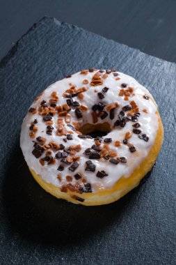 Şist yemekleri ve siyah ahşap arka plan üzerinde sırlı kahverengi donut.