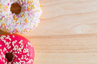 Ahşap arka planda beyaz ve pembe jöleli çörekler.