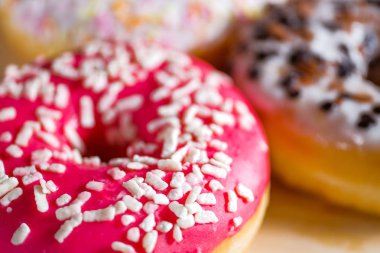 Ahşap arka planda pembe sırlı donutlar.