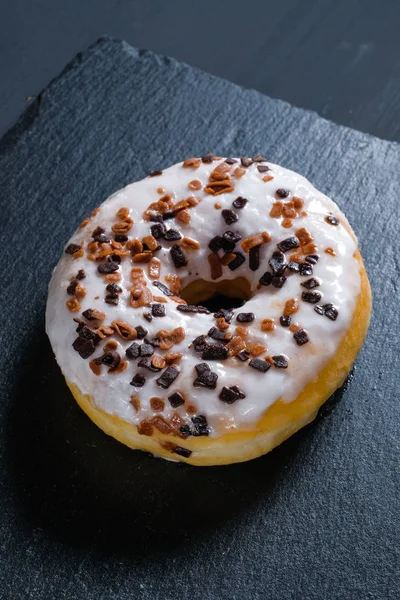 Şist yemekleri ve siyah ahşap arka plan üzerinde sırlı kahverengi donut. — Stok fotoğraf