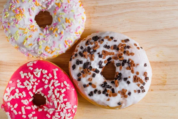 Tahta arka planda beyaz, pembe ve kahverengi donutlar.. — Stok fotoğraf