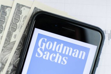 Rusya, St.Petersburg, 4 Nisan 2019: Logo Goldman Sachs Group akıllı telefon yalan grafikler ve dolar faturaları.