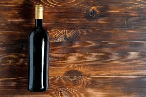 Una botella oscura de vino sobre un fondo de madera . —  Fotos de Stock
