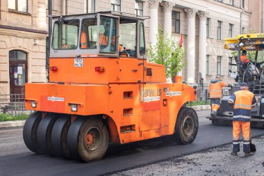 Rusya, St.Petersburg - 12 Mayıs 2019: Yolların onarımı. Tulumlarda iki turuncu asfalt döşeme ve işçi.