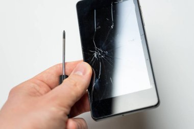Beyaz arka plan önünde erkek elinde kırık ekran ve tornavida ile Akıllı Telefon.