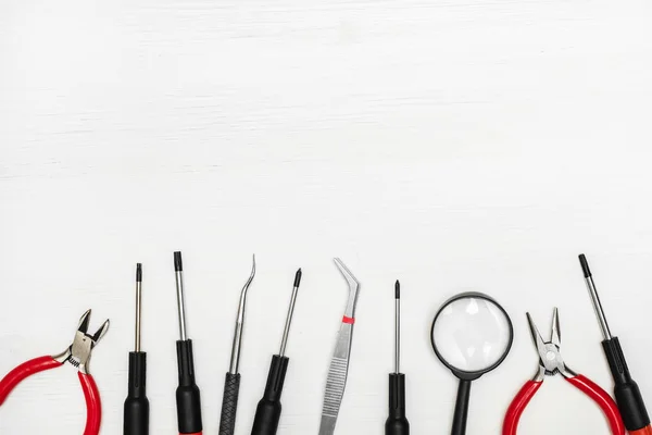 Electronics repair tools are lined in a row at the bottom of the white background.