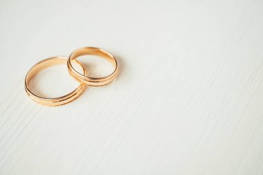 Beyaz ahşap arka plan sol kısmında kesişen alyans altın yüzük. Yan görünüm.