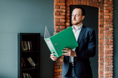 bir takım elbiseli başarılı muhasebeci standları ve raporları ile yeşil bir klasör tutar ve ellerinde bunu dikkate.