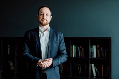 bir takım elbiseli başarılı işadamı elleri katlanmış ile ofiste ayakta.