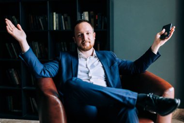 Takım elbiseli başarılı bir işadamı şık bir ofisin sandalyesinde oturuyor. Başarılı bir işlem kavramı.